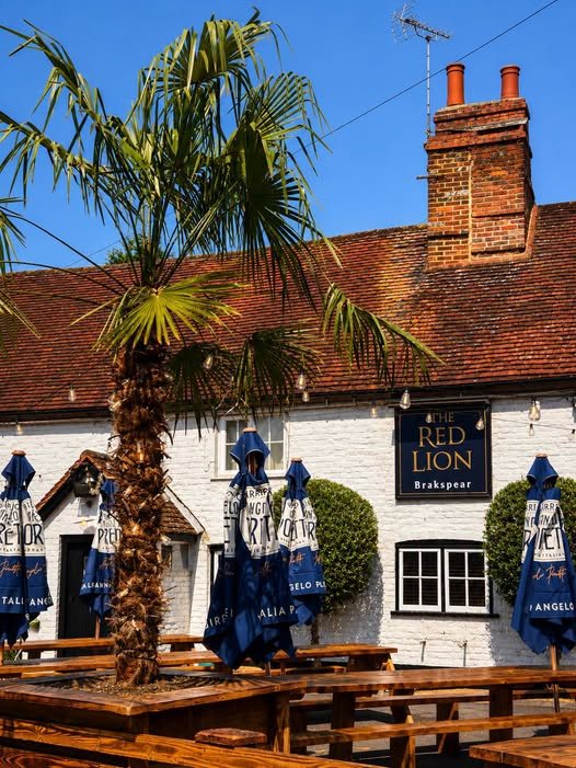 Charming traditional brick exterior facade of The Red Lion pub with flower baskets